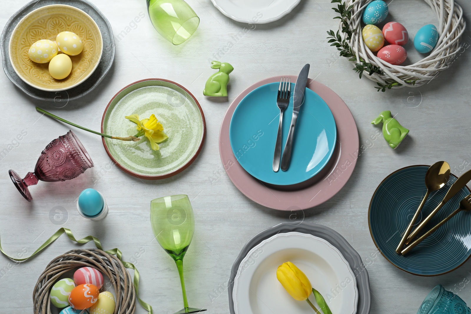 Photo of Festive Easter table setting with painted eggs on wooden background, top view