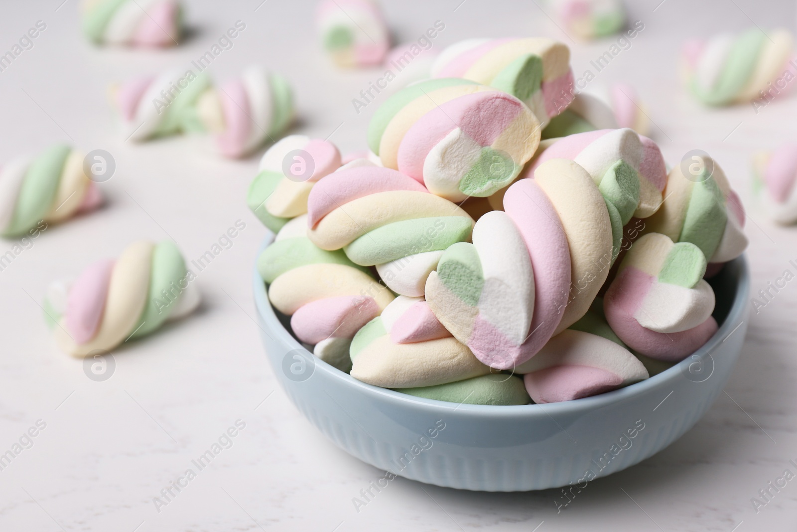 Photo of Bowl with colorful marshmallows on white table, closeup