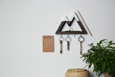 Wooden key holder and to do list on light grey wall indoors. Space for text