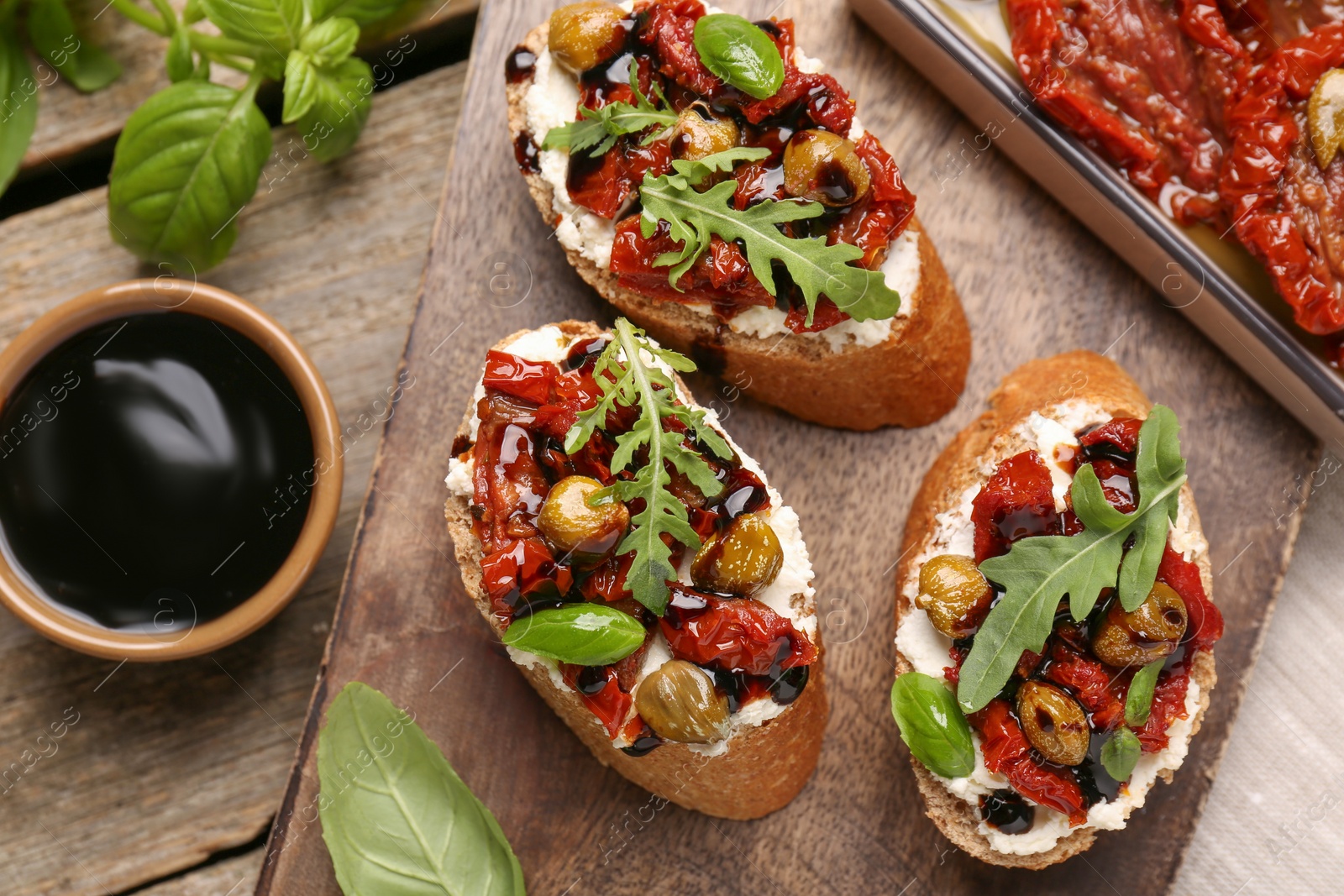 Photo of Delicious bruschettas with balsamic vinegar and toppings served on wooden table, flat lay