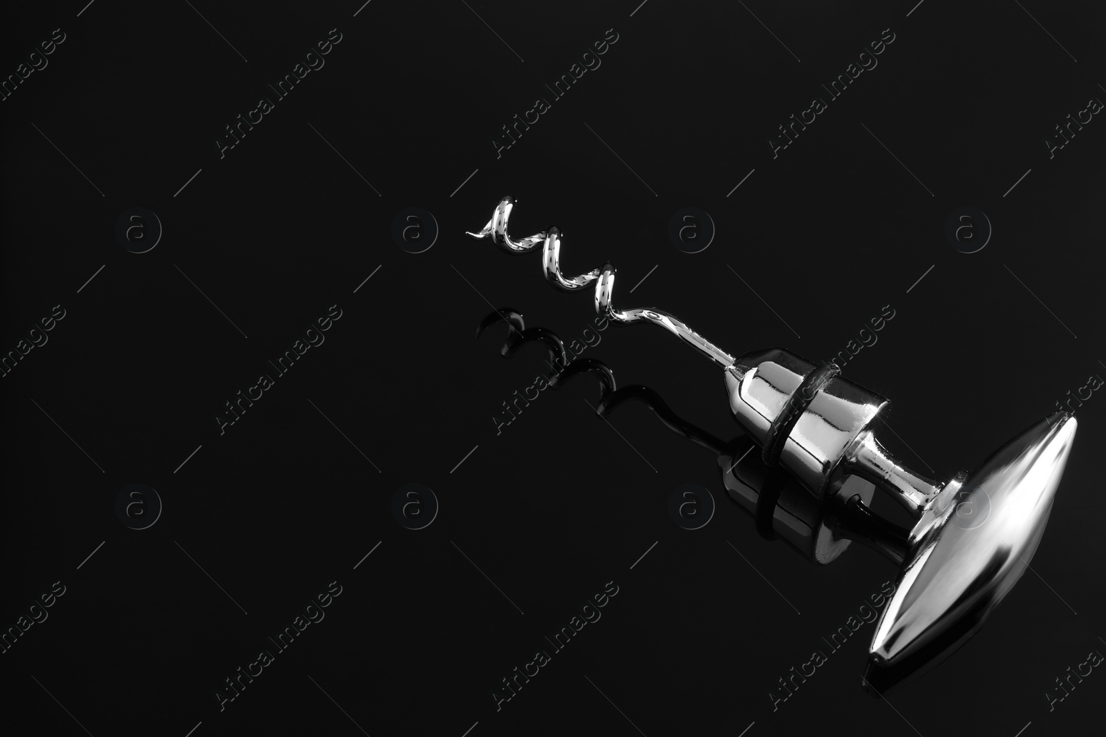 Photo of One metal corkscrew on dark mirror surface, space for text