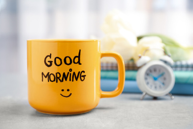 Photo of Cup of coffee with good morning wish on light grey table, closeup