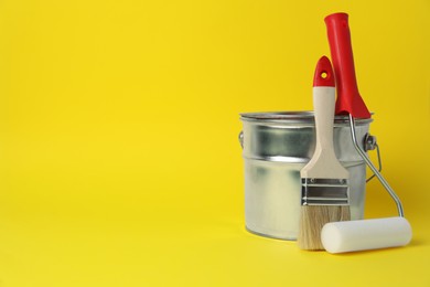 Photo of Bucket of paint, brush and roller on white background. Space for text