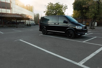 Photo of Black van on parking lot at sunrise outdoors