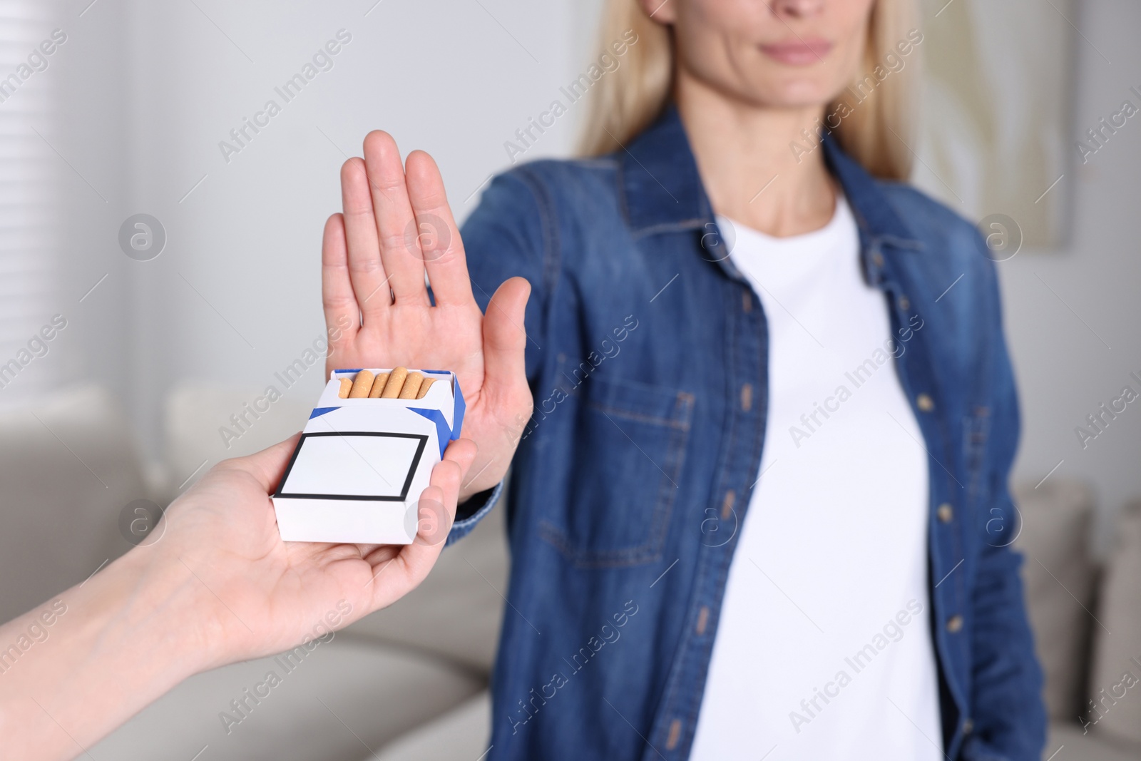 Photo of Woman refusing cigarettes on blurred background, closeup. Quitting smoking concept