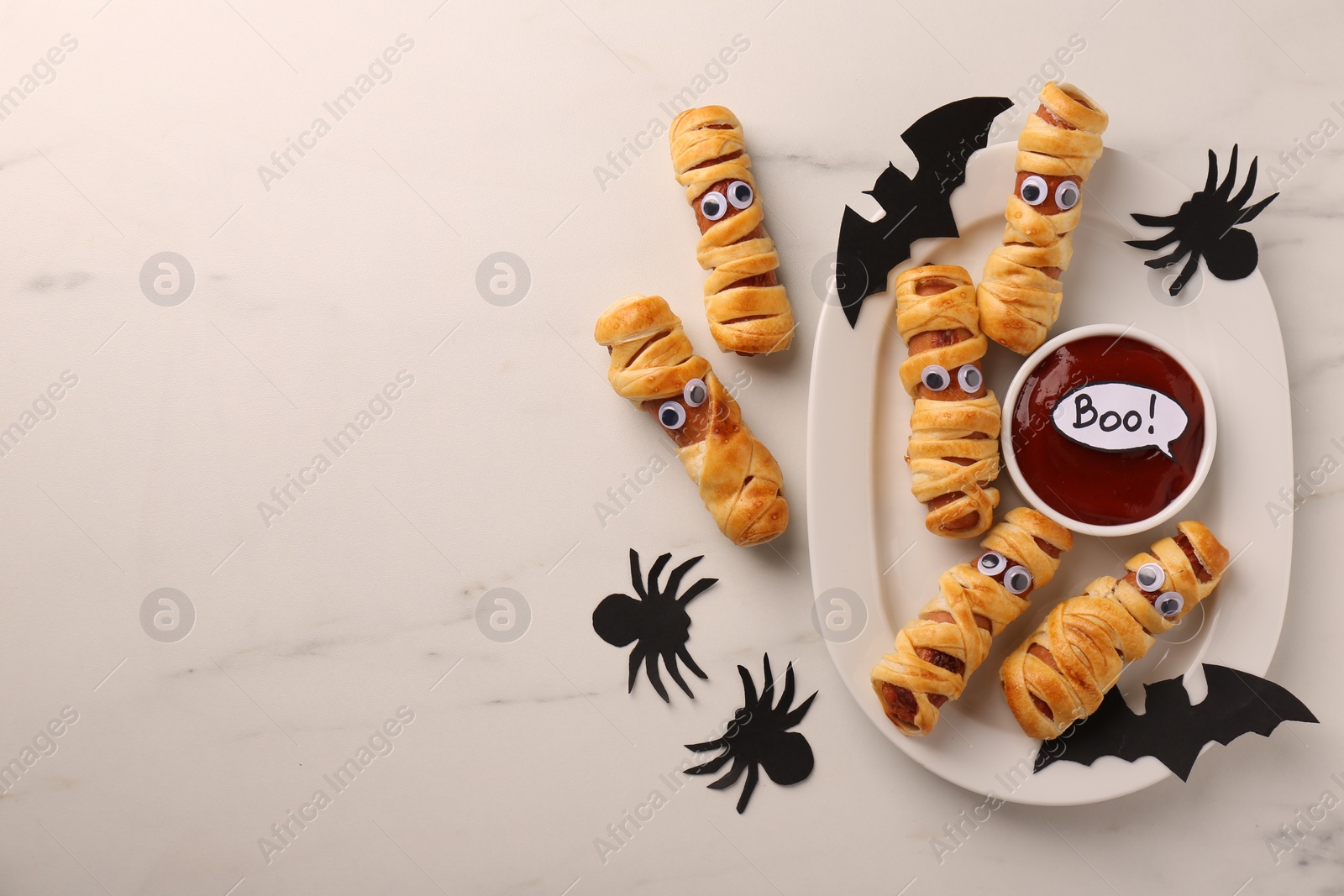 Photo of Flat lay composition with tasty sausage mummies for Halloween party on white marble table. Space for text