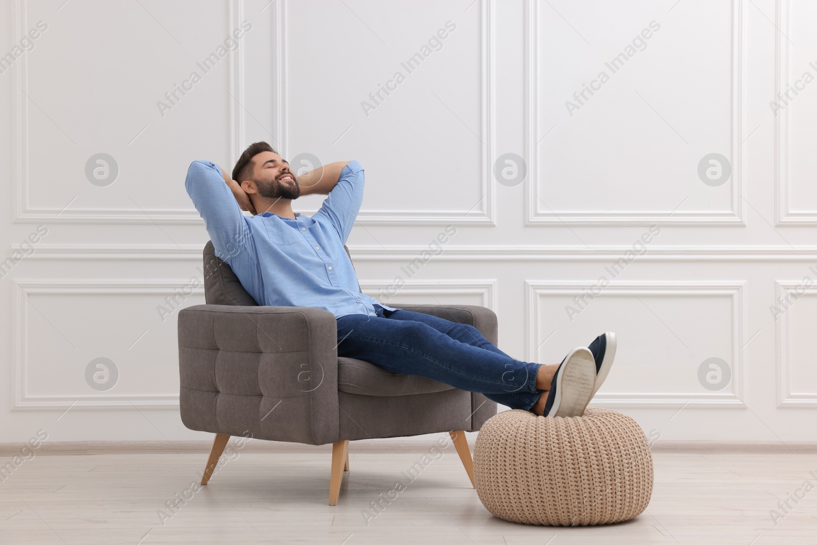 Photo of Handsome man relaxing in armchair near white wall indoors