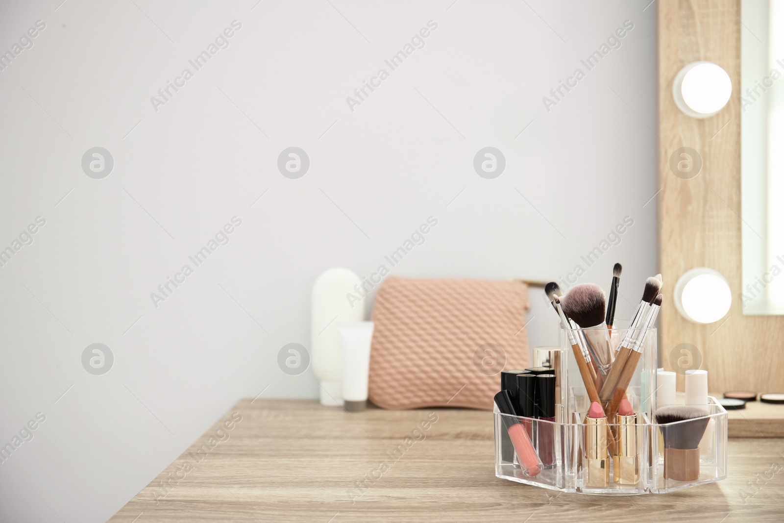 Photo of Makeup cosmetic products with tools in organizer on dressing table. Space for text