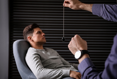 Photo of Psychotherapist using pendulum during hypnotherapy   session in office