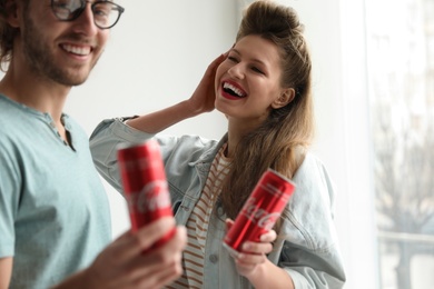 Photo of MYKOLAIV, UKRAINE - NOVEMBER 28, 2018: Young couple with Coca-Cola cans indoors