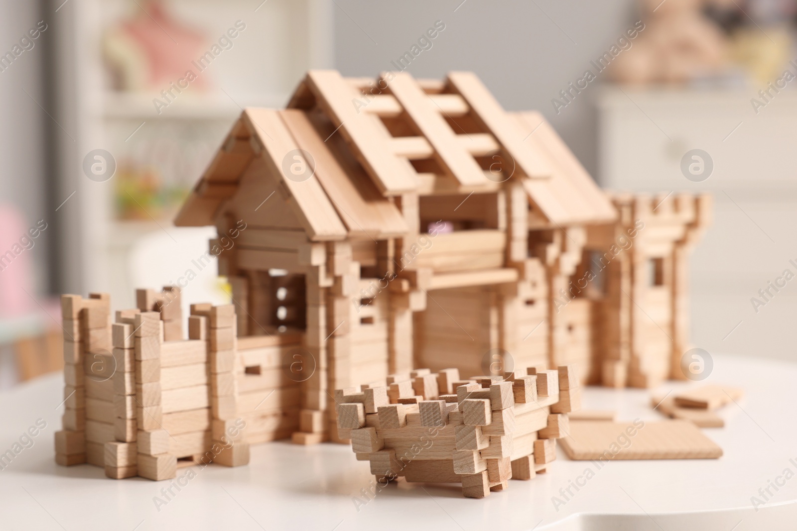 Photo of Wooden entry gate and building blocks on white table indoors. Children's toy