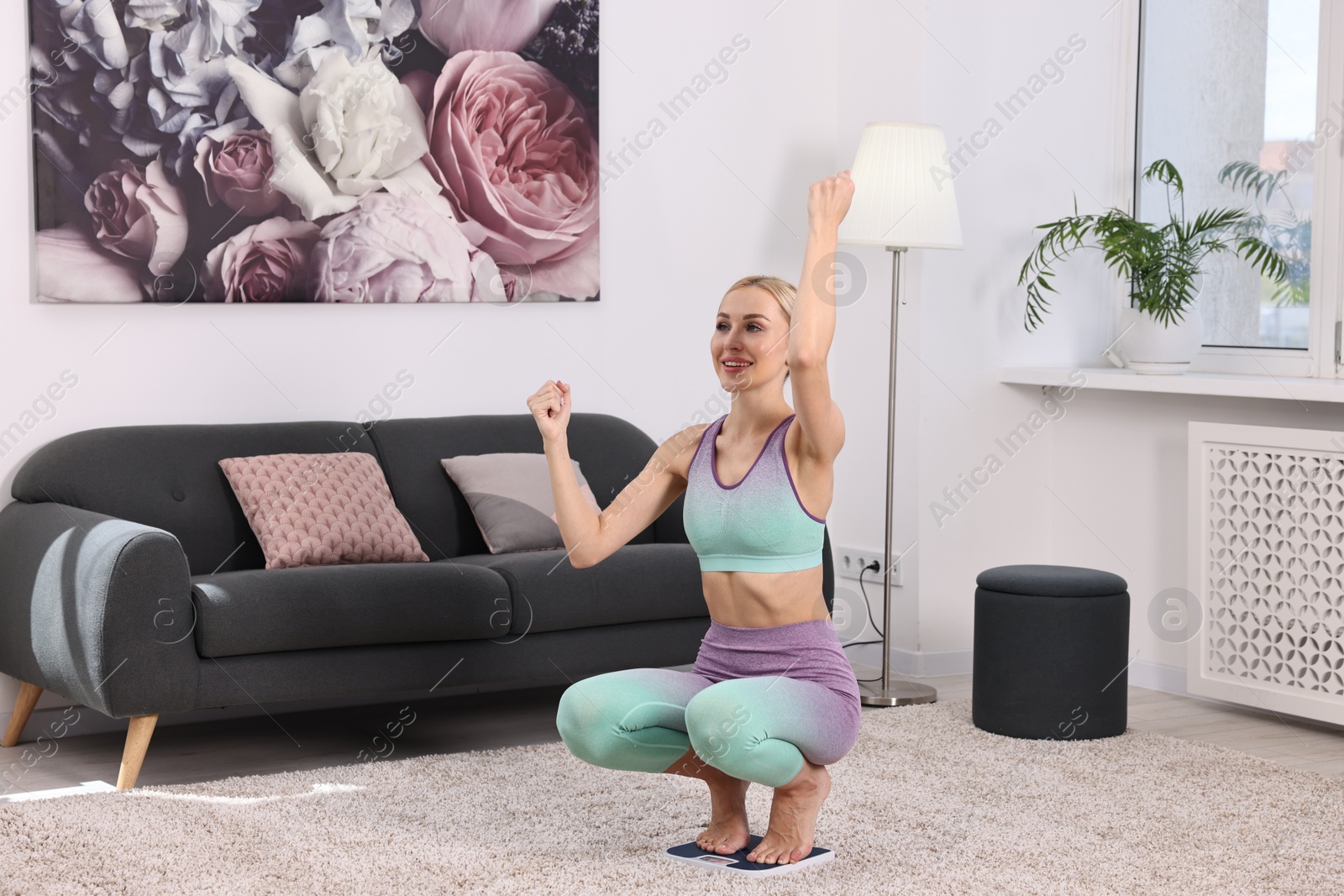 Photo of Happy woman on floor scale at home