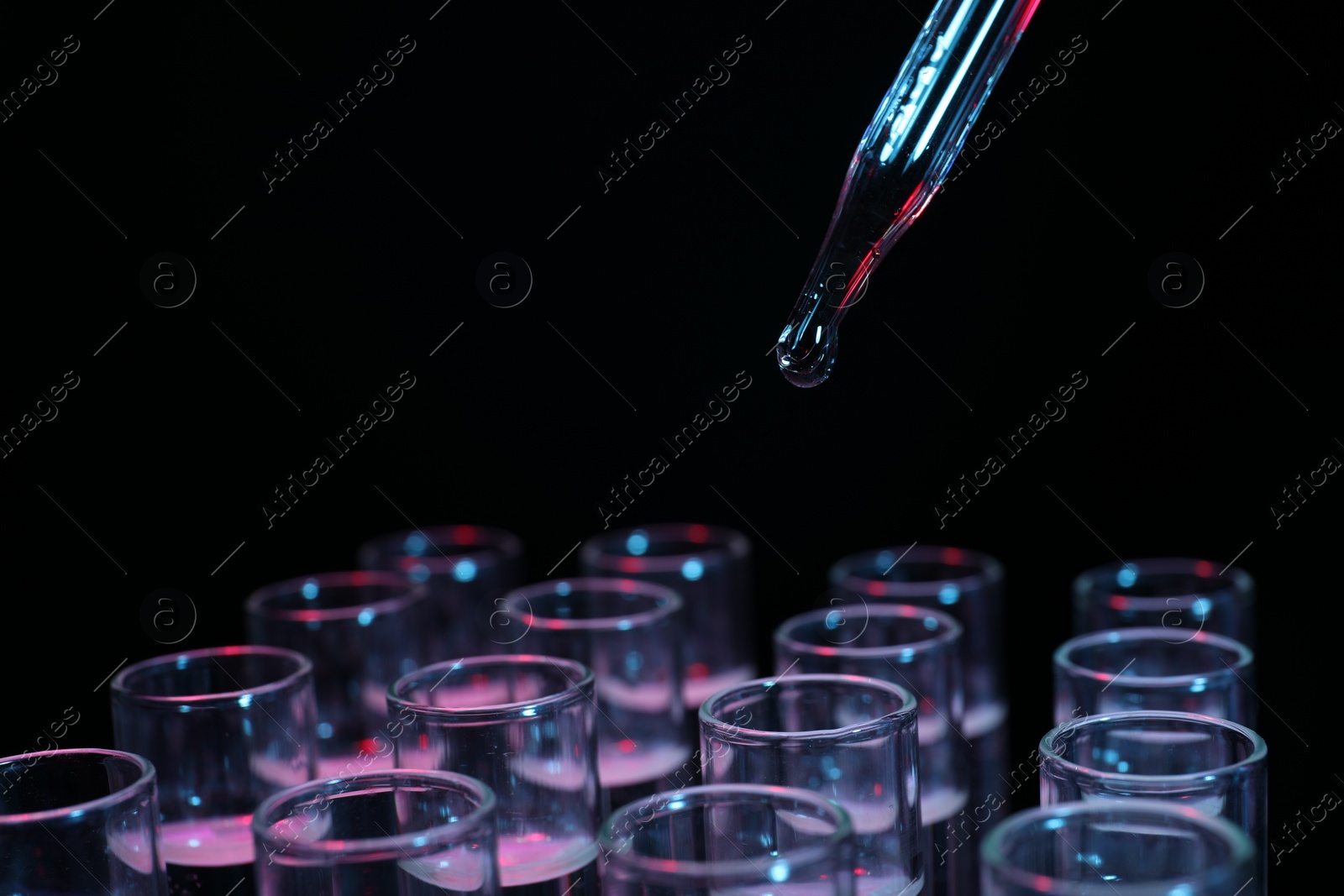 Photo of Dripping reagent into test tube on black background, closeup. Laboratory analysis