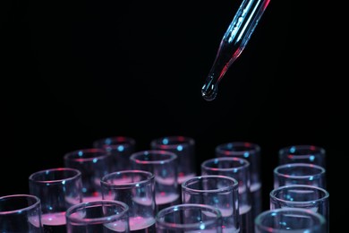 Photo of Dripping reagent into test tube on black background, closeup. Laboratory analysis