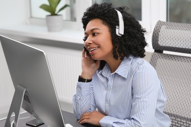 Young woman with headphones working on computer in office
