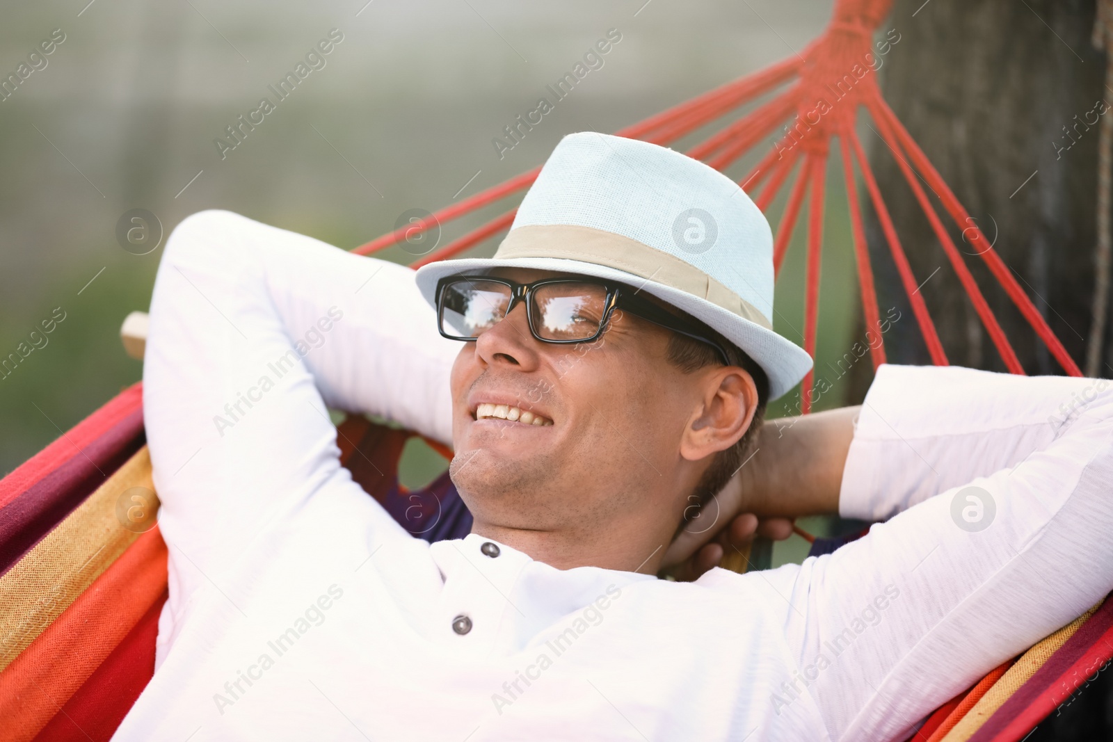 Photo of Man resting in comfortable hammock at green garden