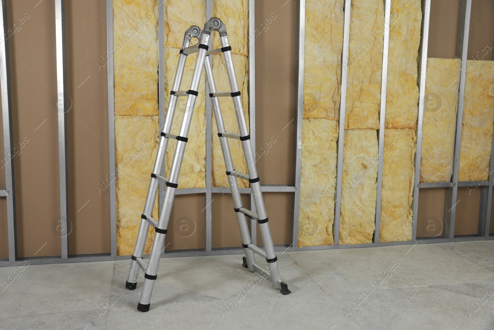 Photo of Ladder near wall with metal studs and insulation material indoors