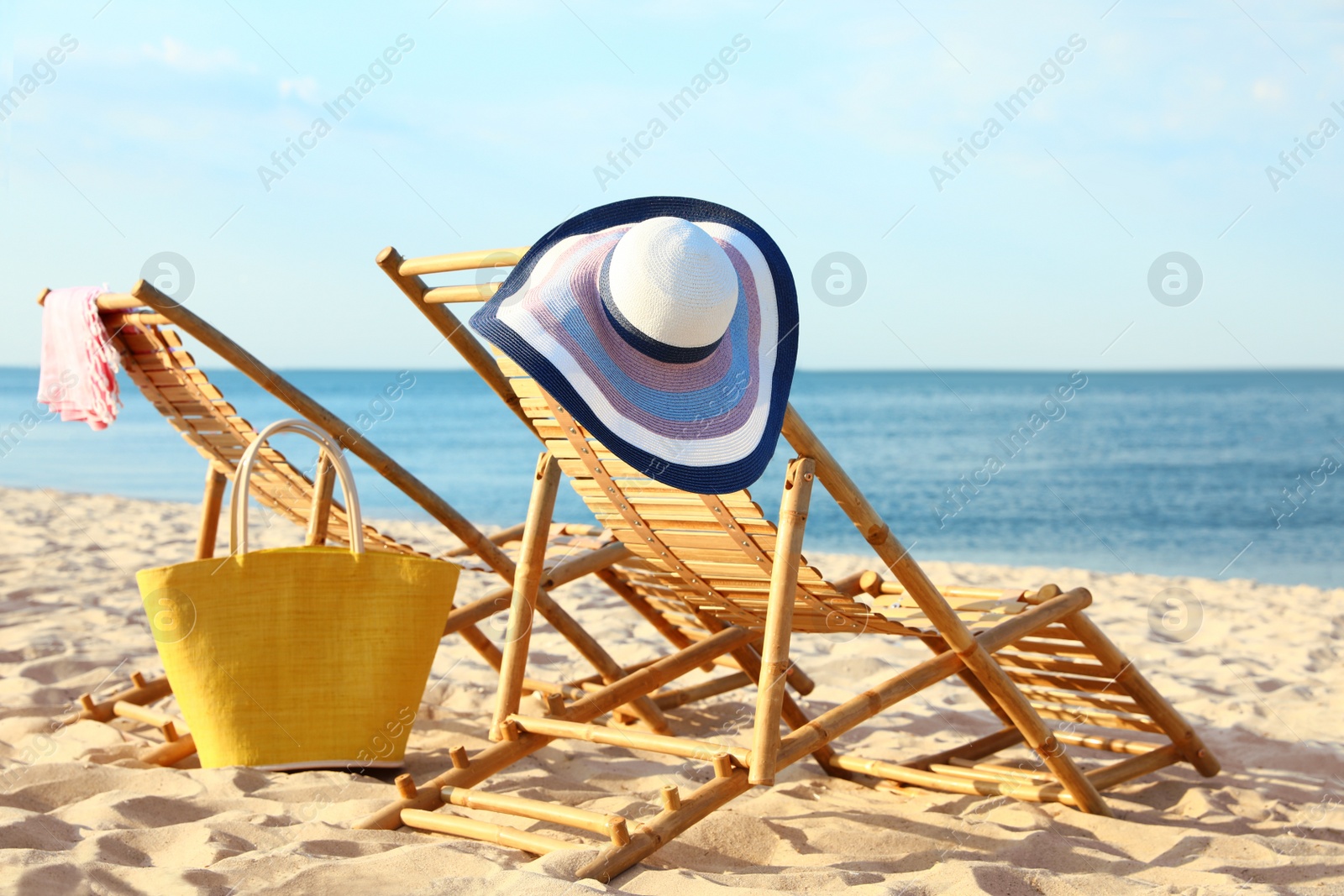 Photo of Empty wooden sunbeds and beach accessories on sandy shore