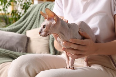 Photo of Woman with cute Sphynx cat on sofa at home, closeup. Lovely pet