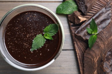 Glass of delicious hot chocolate with fresh mint on wooden table, top view