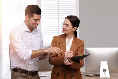 Businesswoman helping intern with work in office