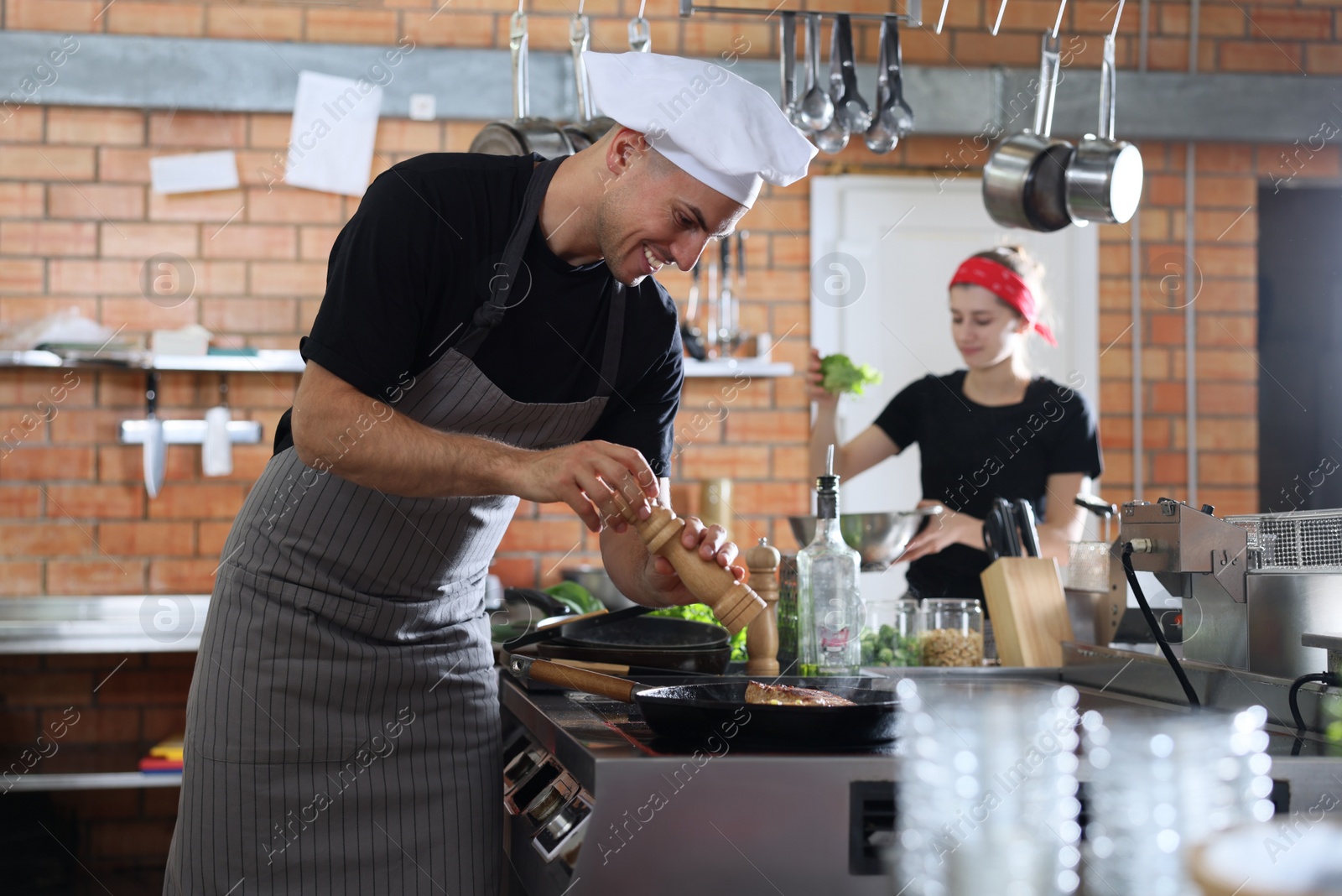 Photo of Professional chef cooking meat on stove in restaurant kitchen