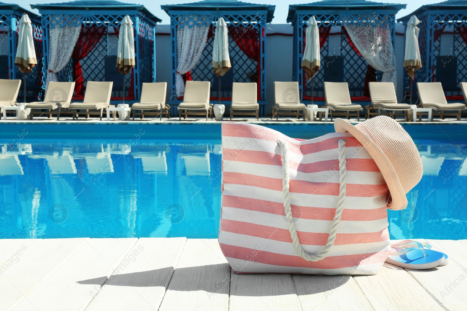 Photo of Beach accessories on wooden deck near swimming pool. Space for text