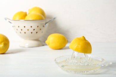 Photo of Ripe lemons and juicer on table against light background