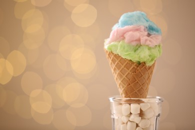 Sweet cotton candy in waffle cone against blurred lights, closeup. Space for text