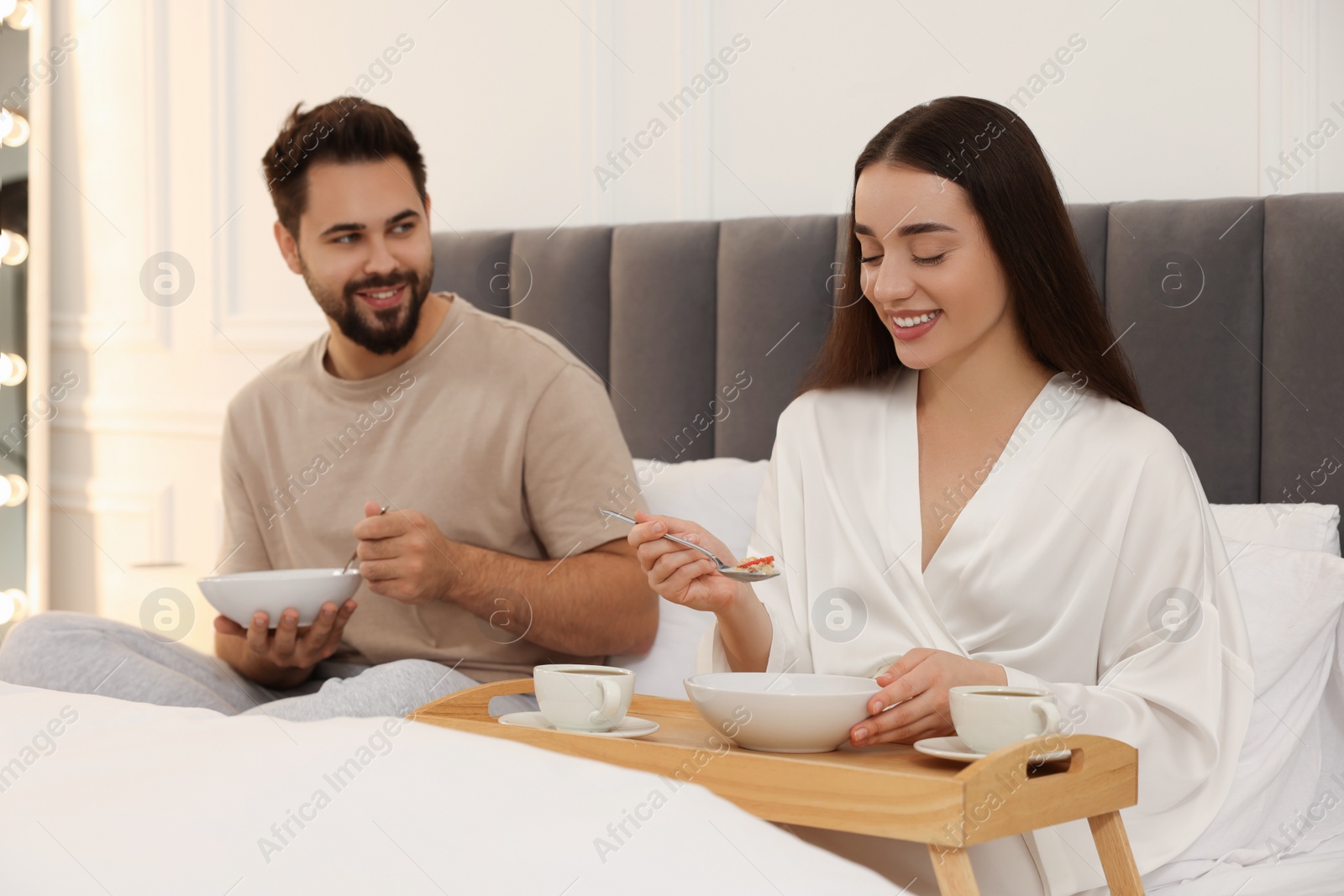 Photo of Happy couple having breakfast on bed at home