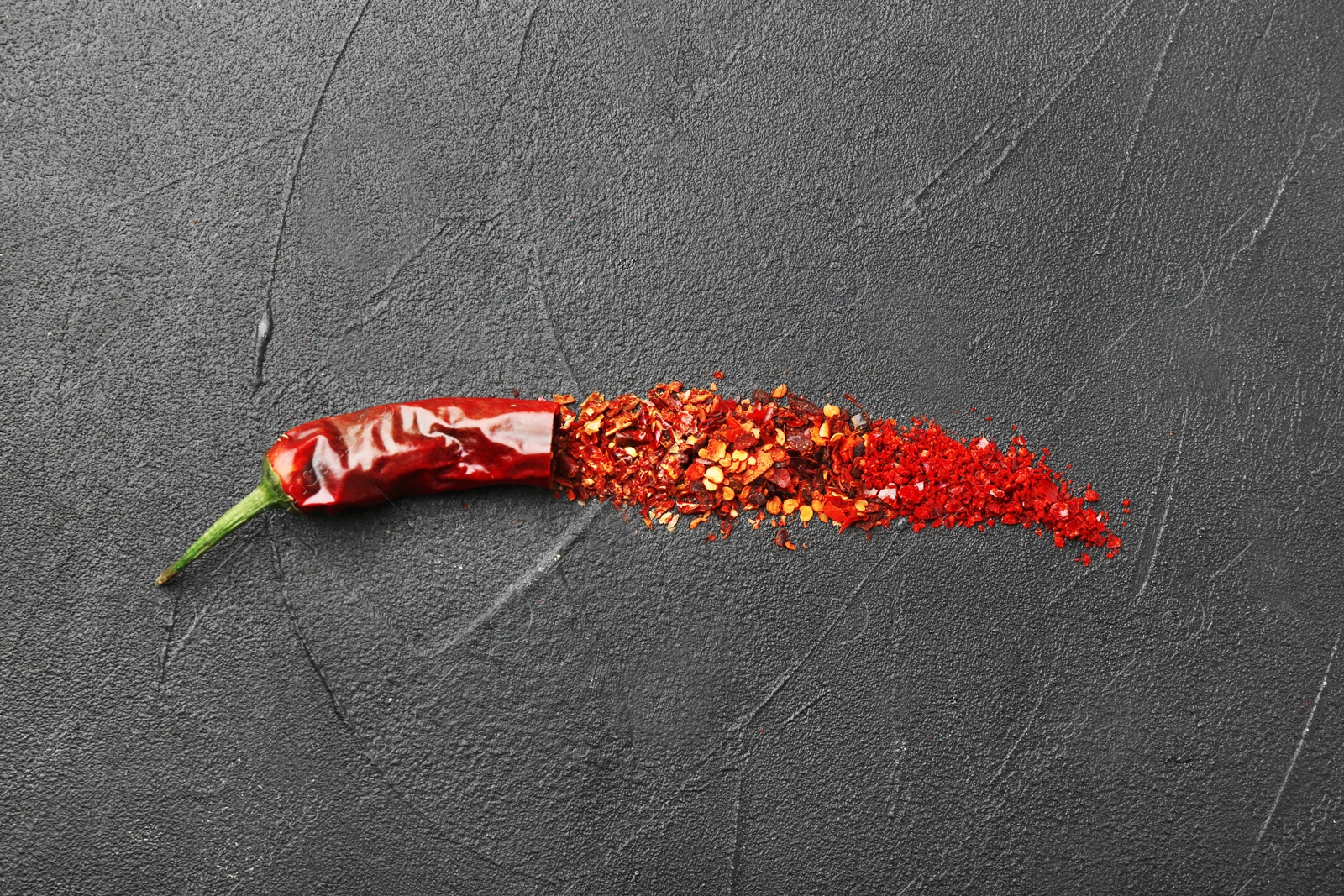 Photo of Composition with chili pepper flakes on grey background, top view