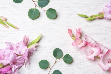 Photo of Flat lay composition with beautiful gladiolus flowers and leaves on wooden background