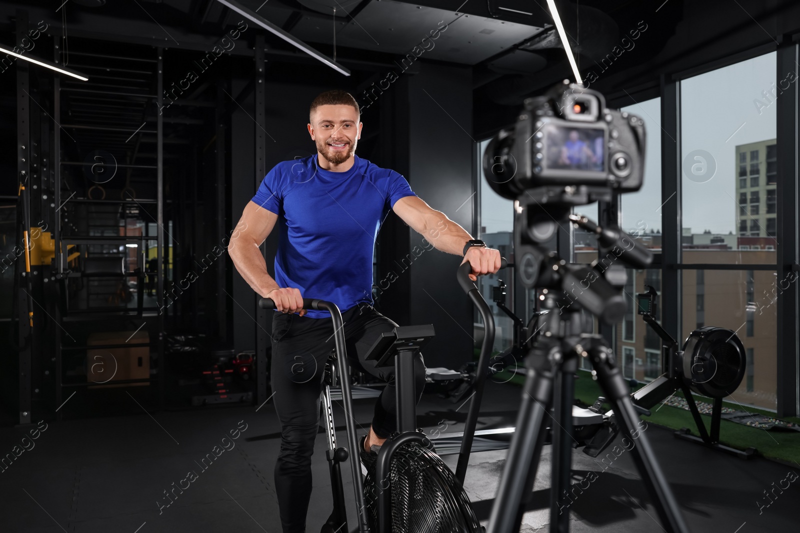 Photo of Man recording workout on camera at gym. Online fitness trainer