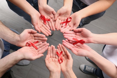 Photo of Group of people holding red awareness ribbons indoors, above view. World AIDS disease day