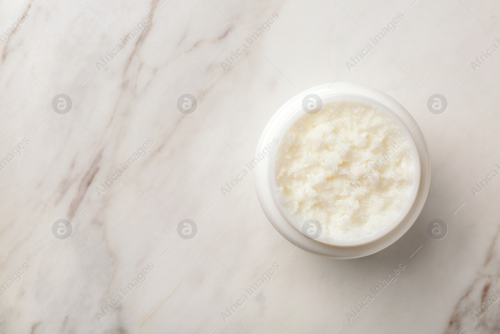 Photo of Jar of shea butter and space for text on marble background, top view