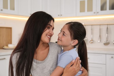 Happy mother and daughter hugging in kitchen. Single parenting