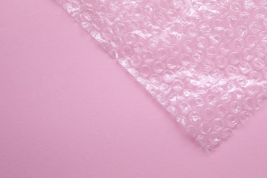 Photo of Transparent bubble wrap on pink background, top view. Space for text