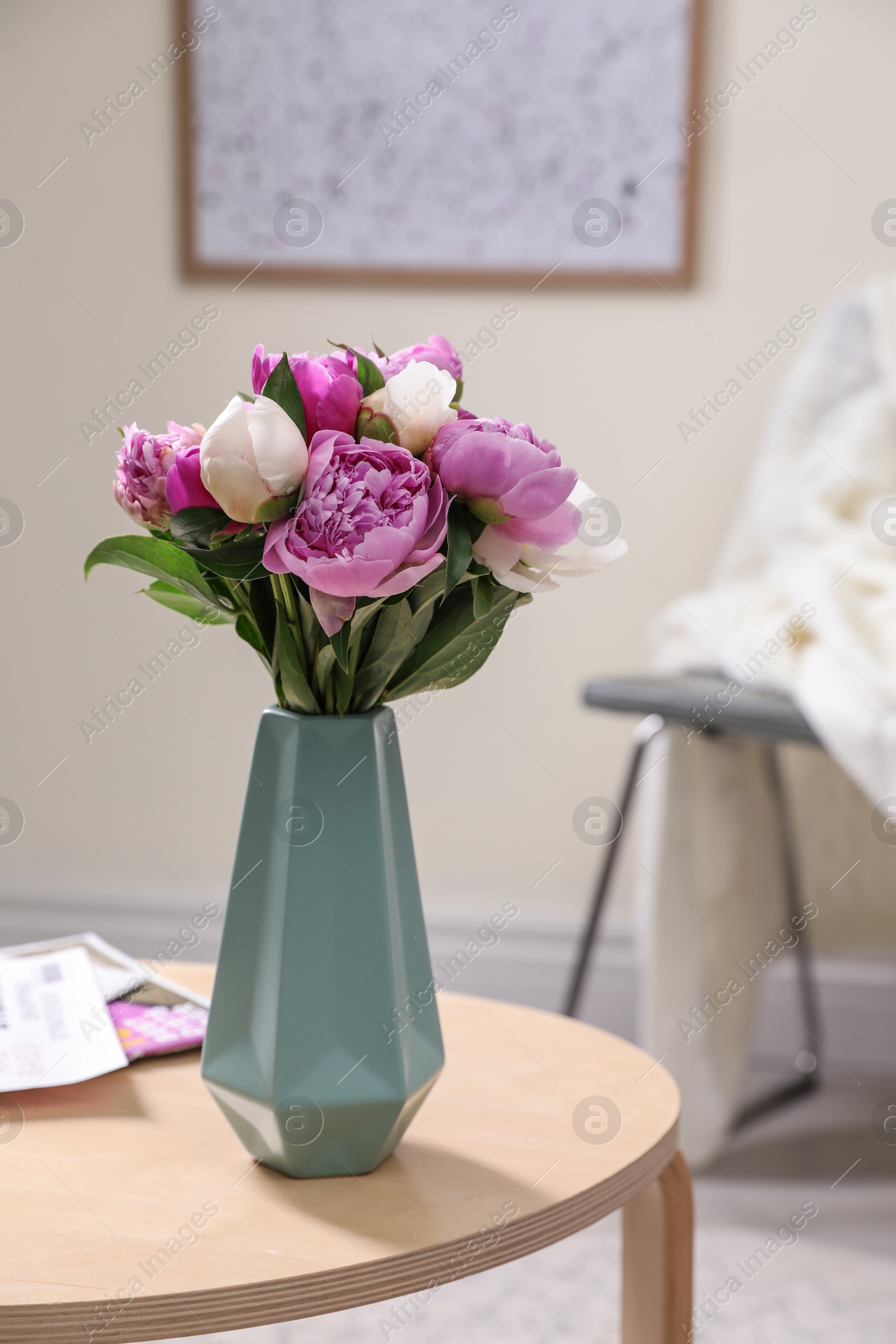 Photo of Vase with bouquet of beautiful peonies on table in room