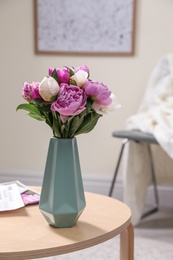 Photo of Vase with bouquet of beautiful peonies on table in room