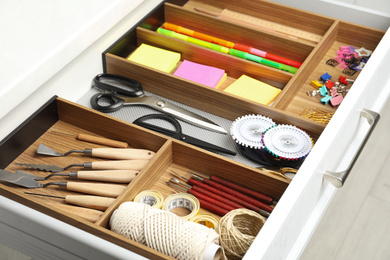 Photo of Sewing accessories and stationery in open desk drawer indoors