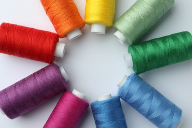Photo of Frame of different colorful sewing threads on white background, top view. Space for text