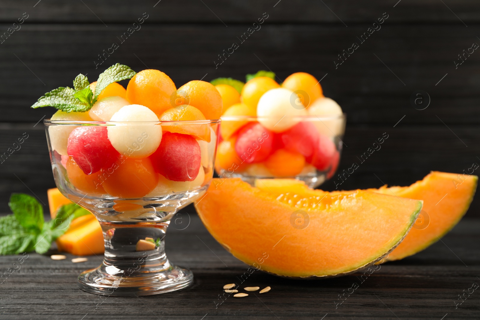 Photo of Melon and watermelon balls with mint in dessert bowl on black wooden table