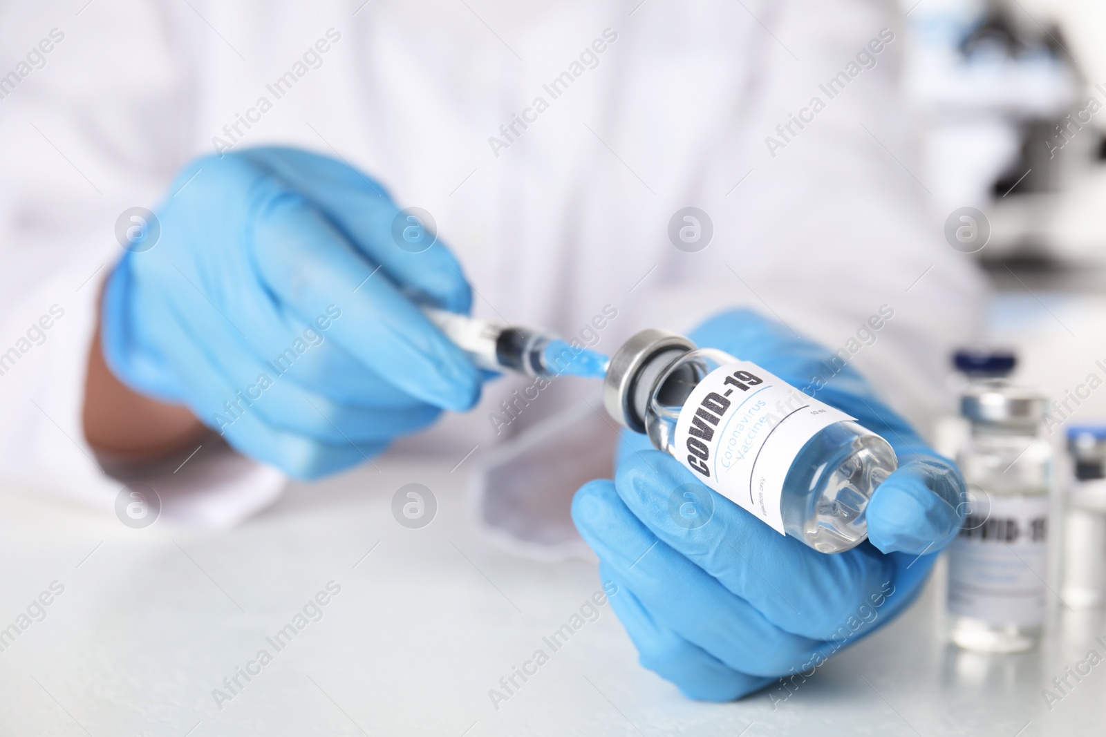 Photo of Doctor filling syringe with vaccine against Covid-19 at table, closeup