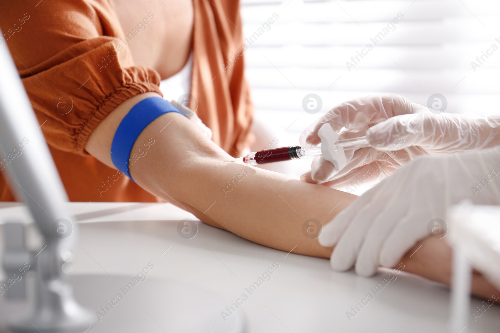 Photo of Nurse drawing blood sample from patient in clinic, closeup