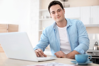 Photo of Portrait of confident young man with  laptop at table