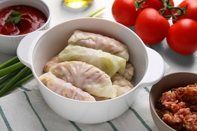 Photo of Uncooked stuffed cabbage rolls and ingredients on table