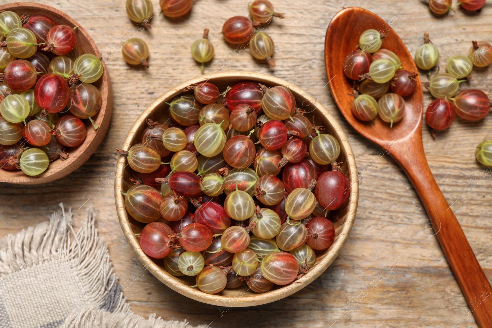 Photo of Many fresh ripe gooseberries on wooden table, flat lay