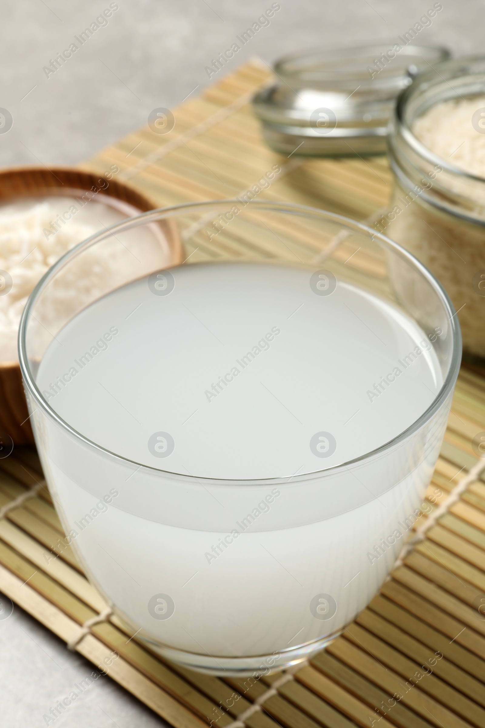 Photo of Glass with natural rice water on bamboo mat, closeup