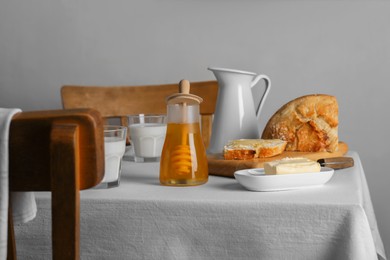 Delicious honey, milk and bread with butter served for breakfast on table indoors