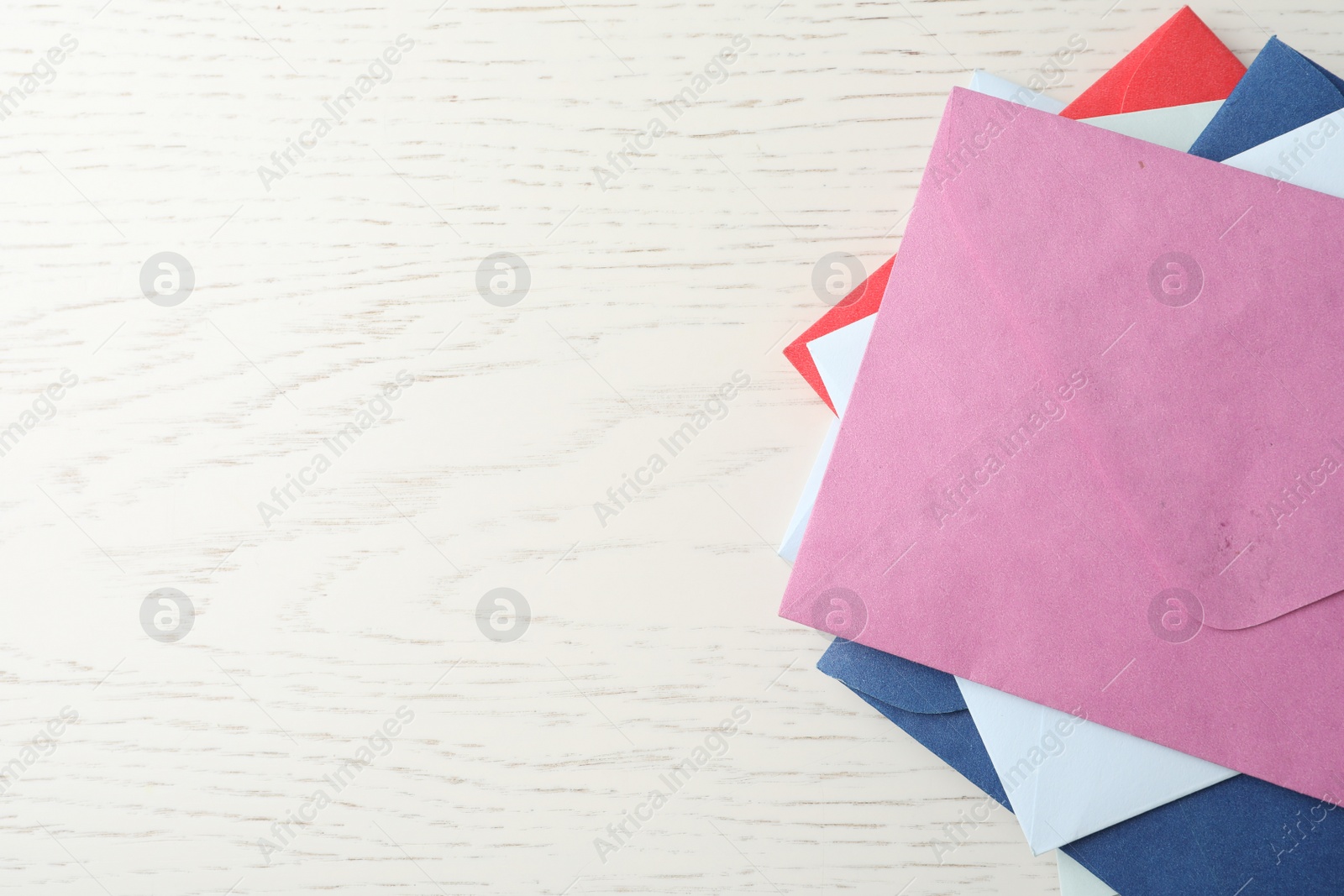 Photo of Colorful paper envelopes on white wooden background, top view. Space for text